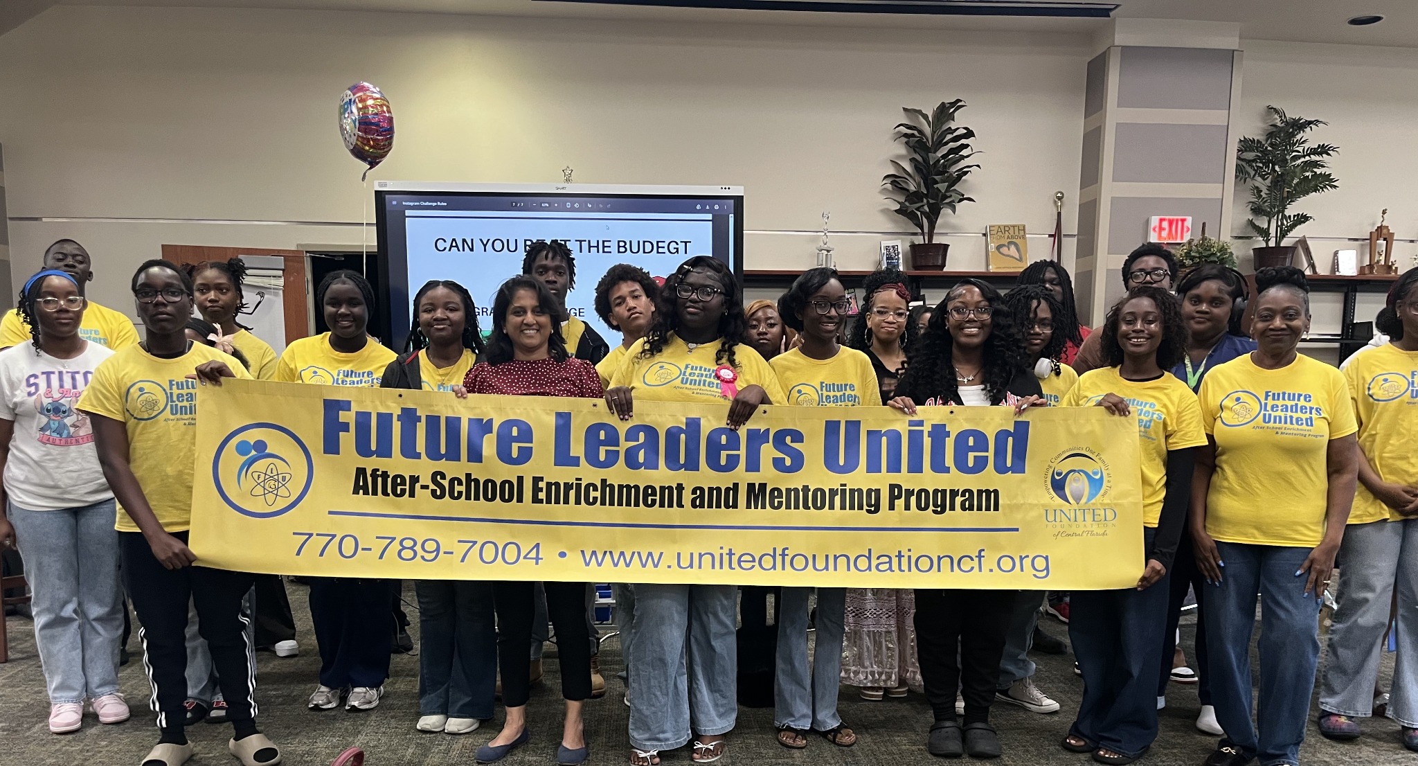FLU students and team pictured with the program banner